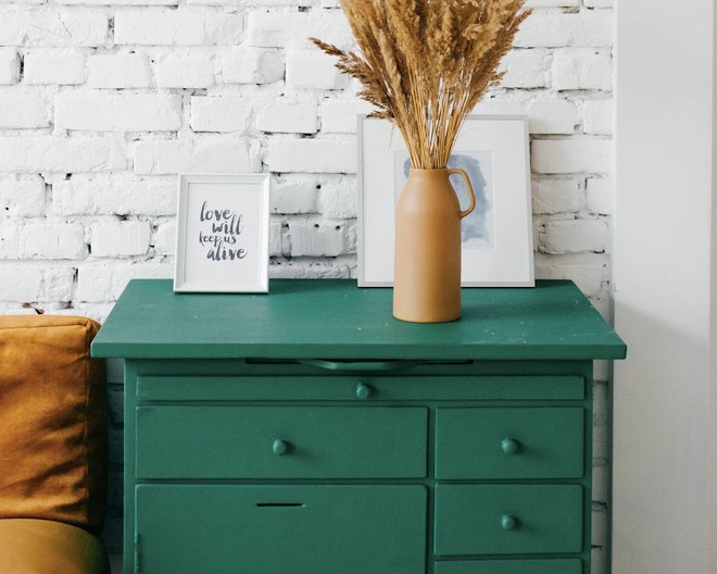 Image of a green drawer, a plant on top, and a picture frame with the words: love will keep us alive.